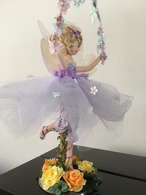 Fada em pé com arco de flores e borboletas nas mãos