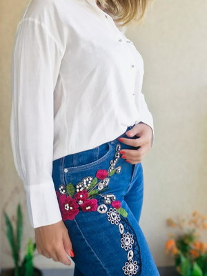 Calça jeans pantacourt com aplique de flores