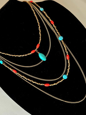 Colar dourado com correntes e peças azuis