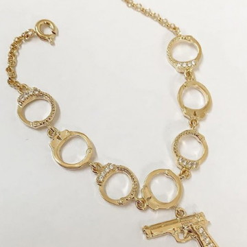 Pulseira algema com pistola cravejada em banho de ouro